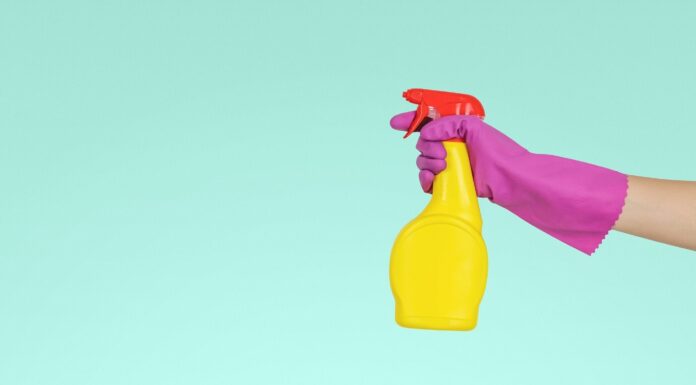 hand covered in a glove holds cleaning spray for spring cleaning
